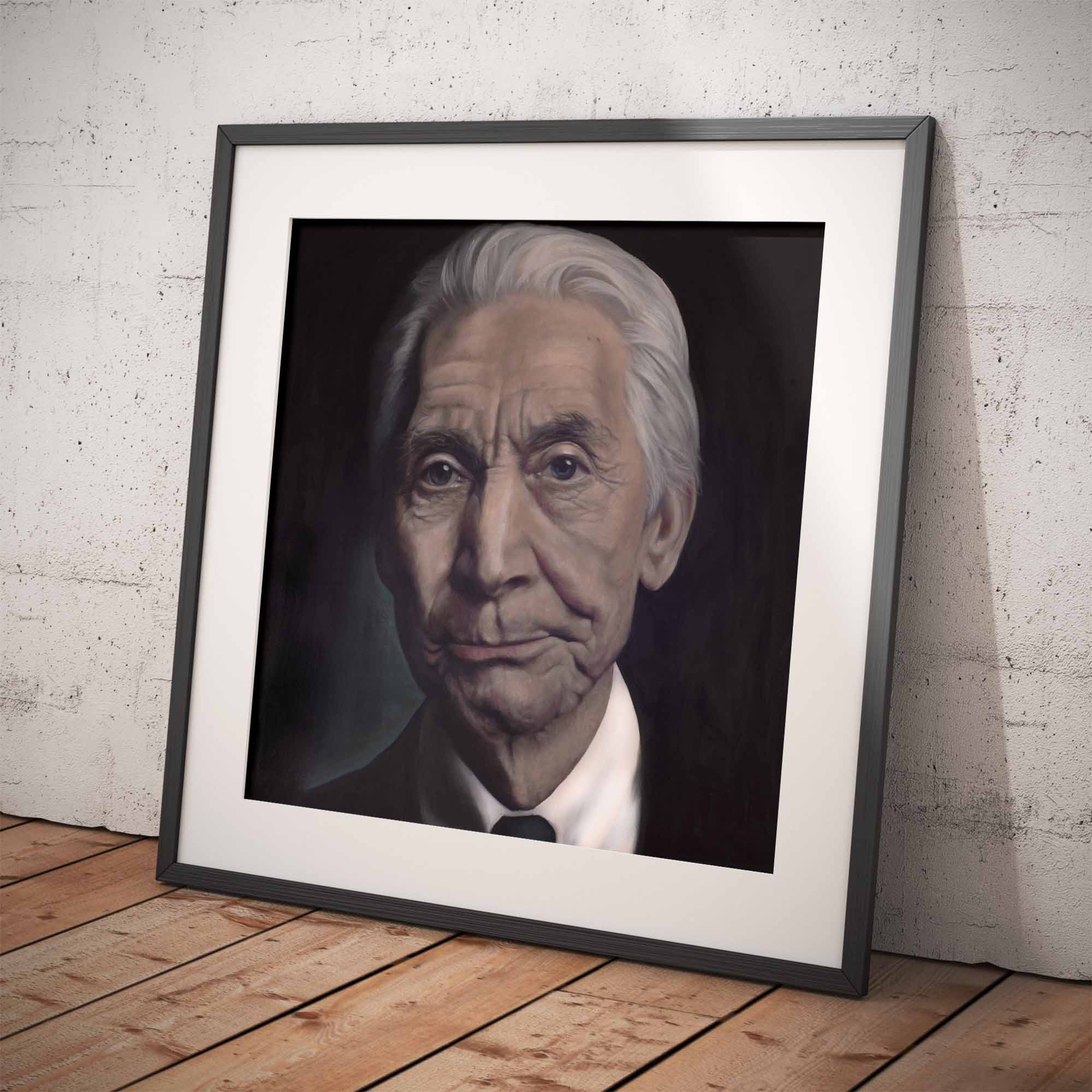 Framed portrait of Charlie Watts on a wooden floor with a white brick wall background
