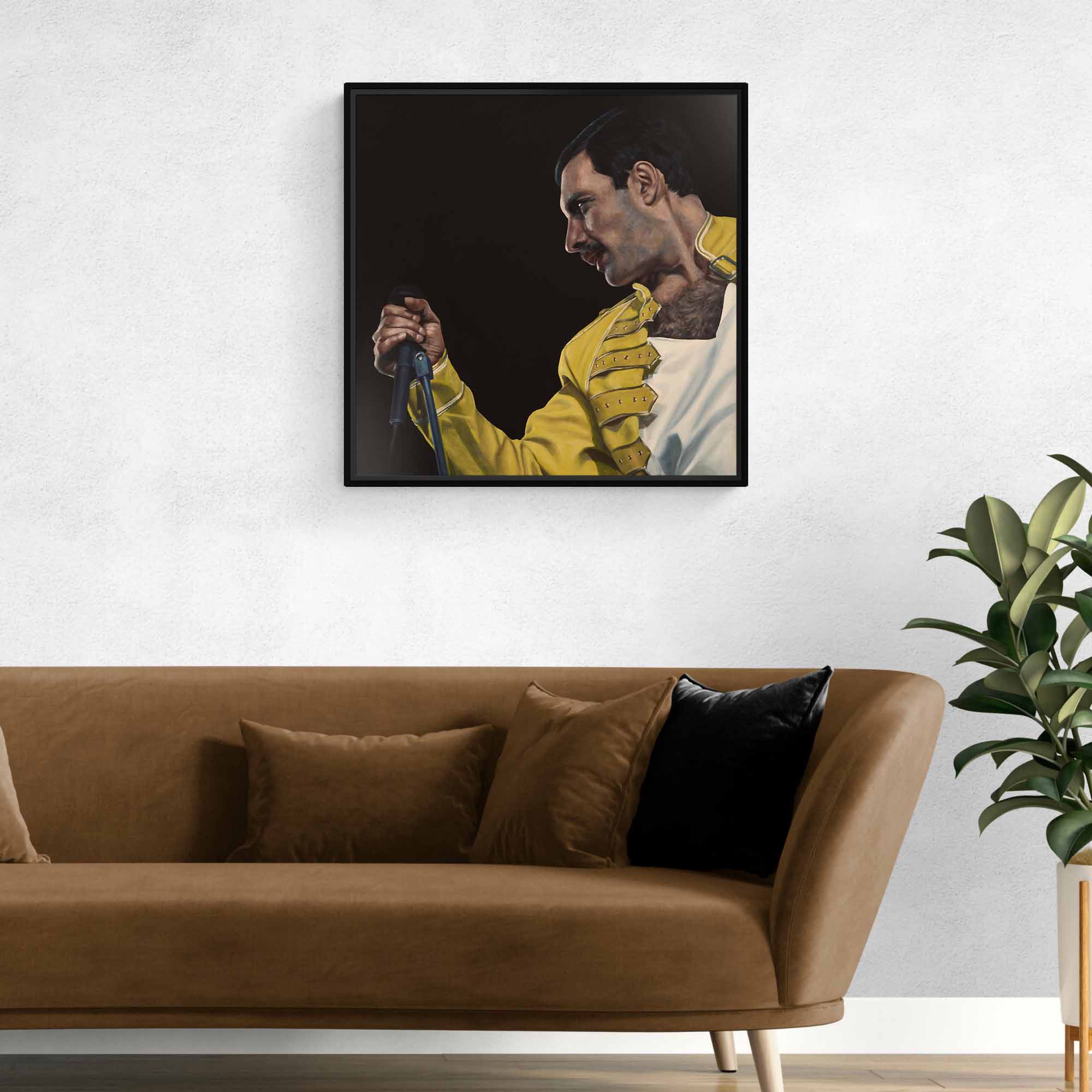 Framed artwork of Freddie Mercury in a yellow jacket on a wall above a brown sofa.