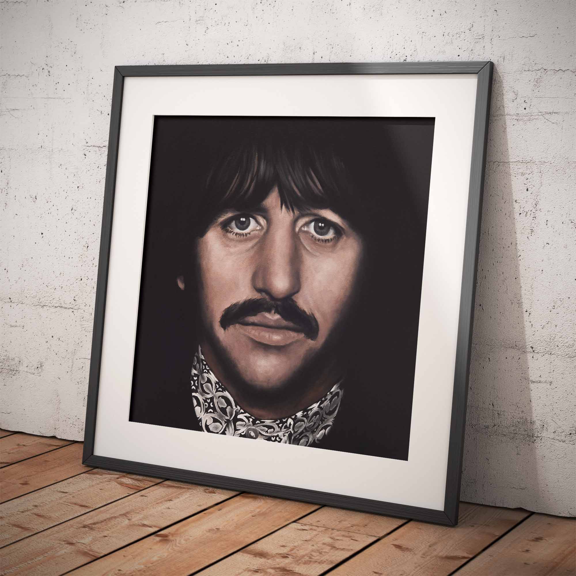 Framed portrait of Ringo Starr on a wooden floor against a white brick wall.