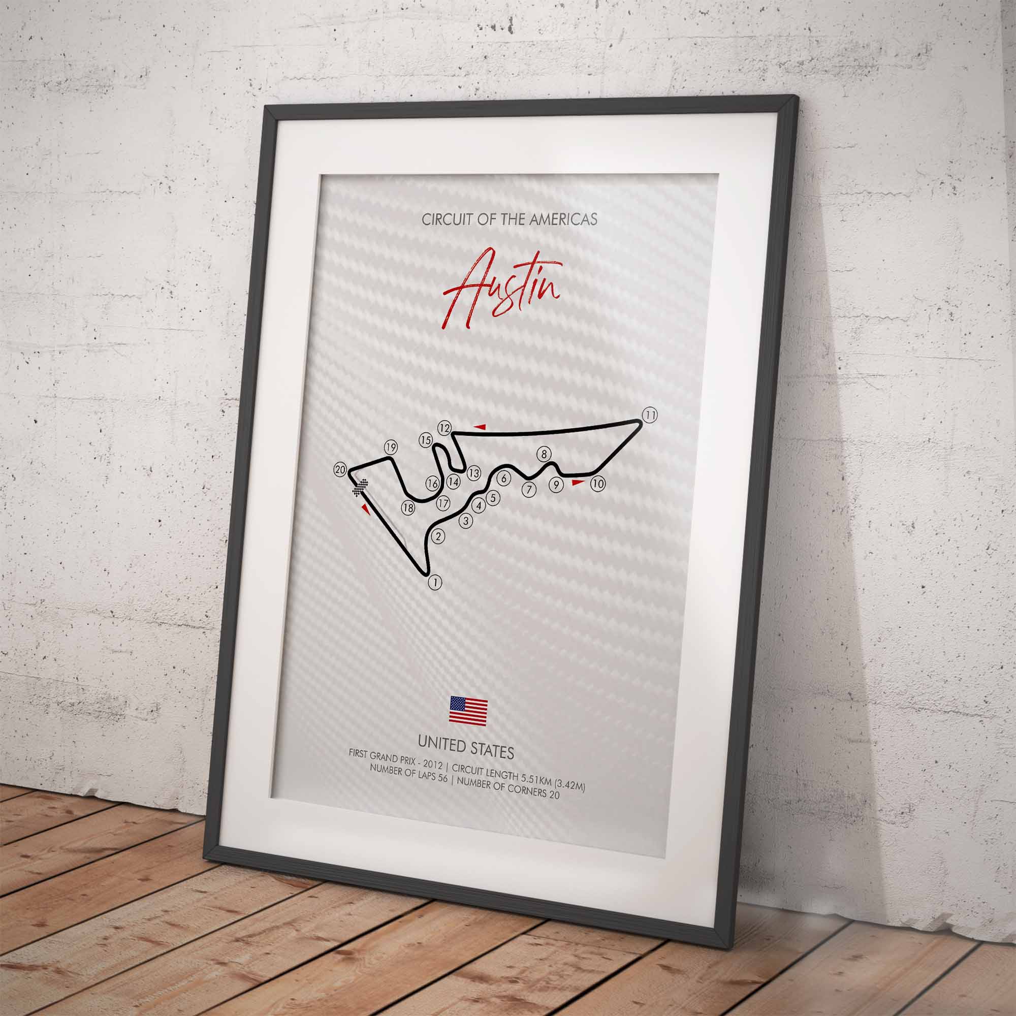 Framed poster of the Circuit of the Americas race track design leant against a white brick wall.