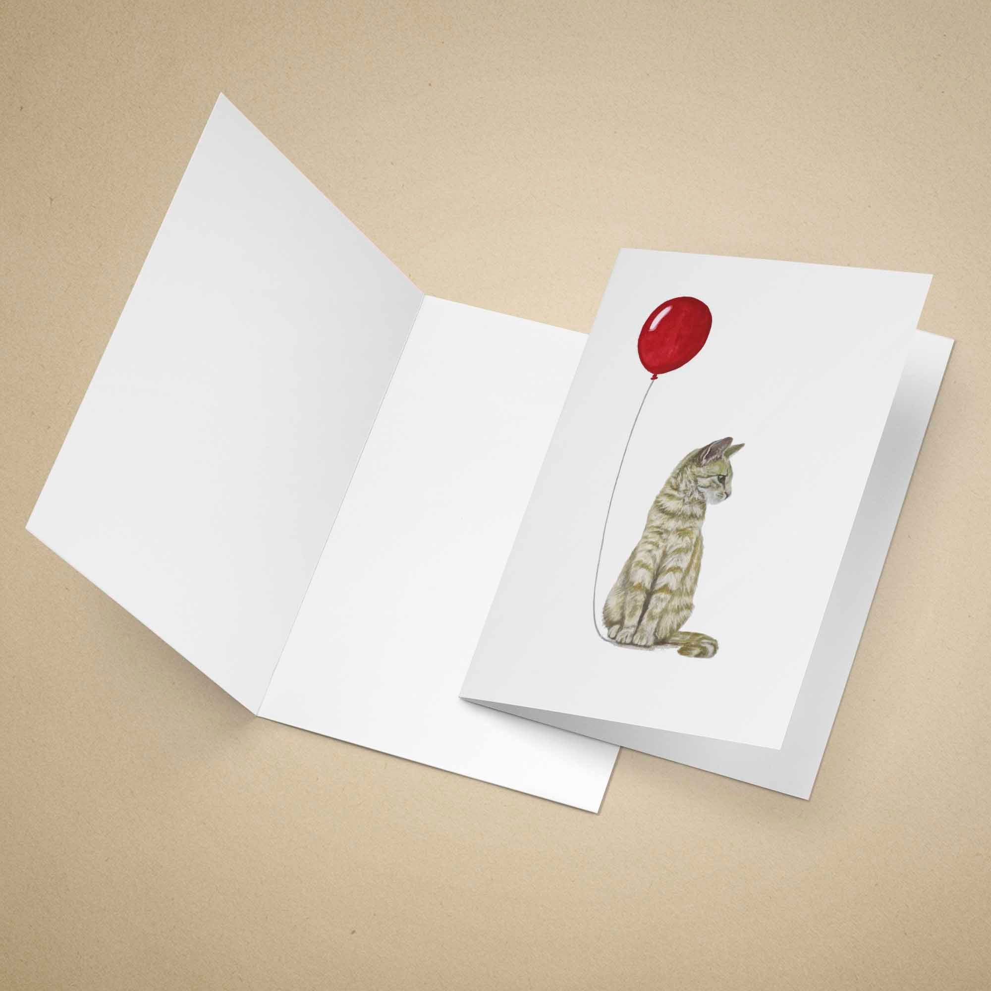 Greeting card with a ginger tabby cat and red balloon design on a beige background
