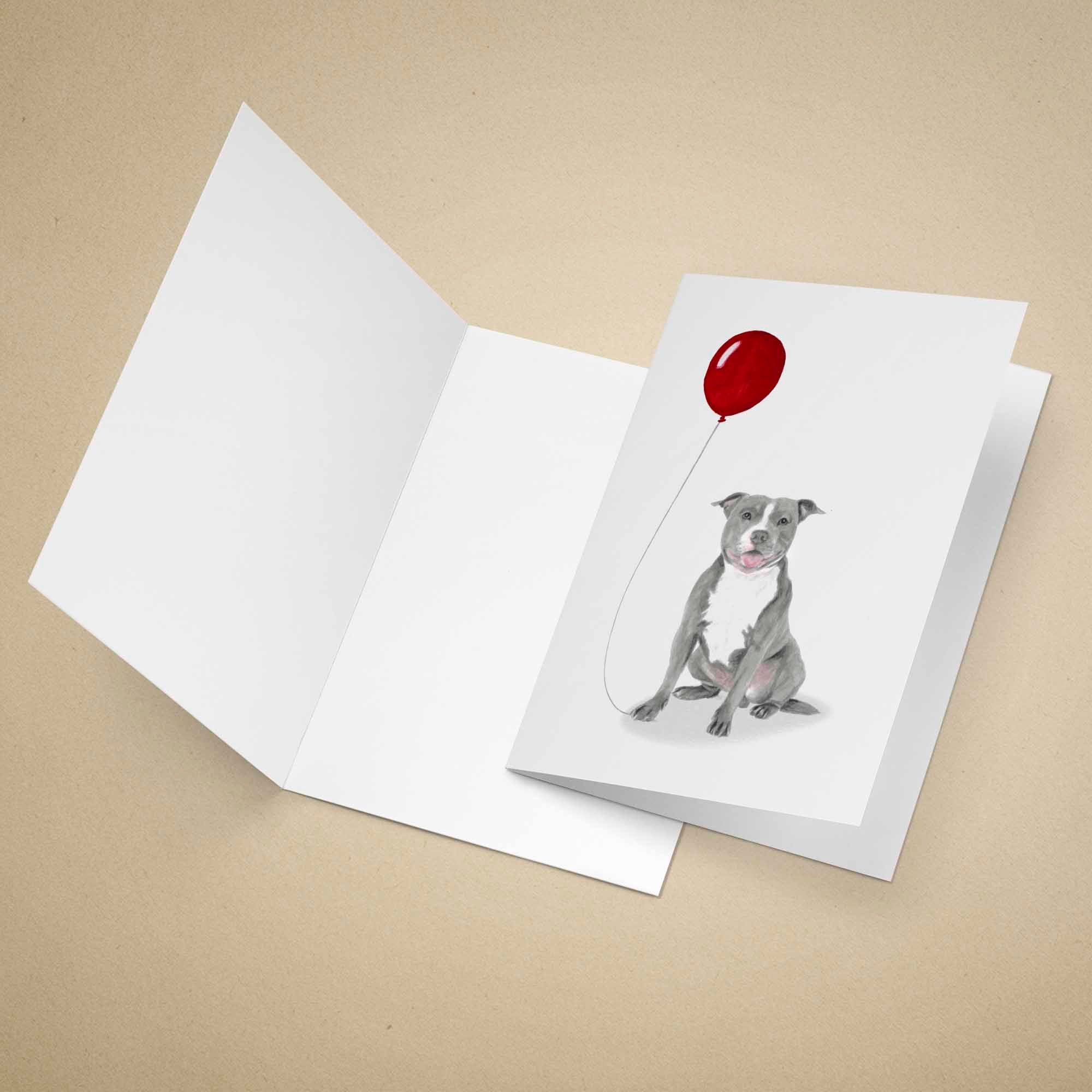 Greeting card with a grey Staffordshire Bull Terrier holding a red balloon on a beige background