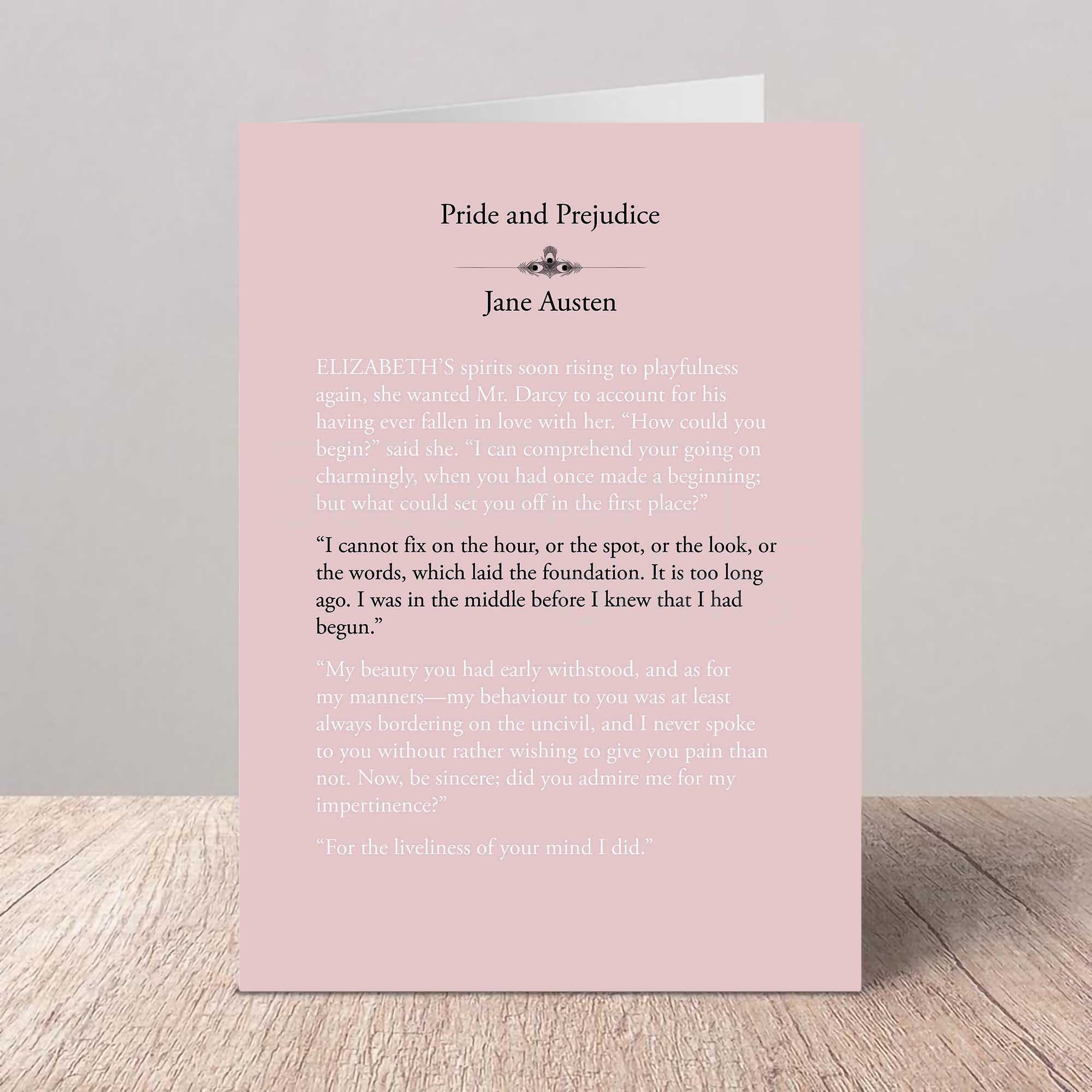 Pink card with text from 'Pride and Prejudice' by Jane Austen on a wooden surface with a gray background