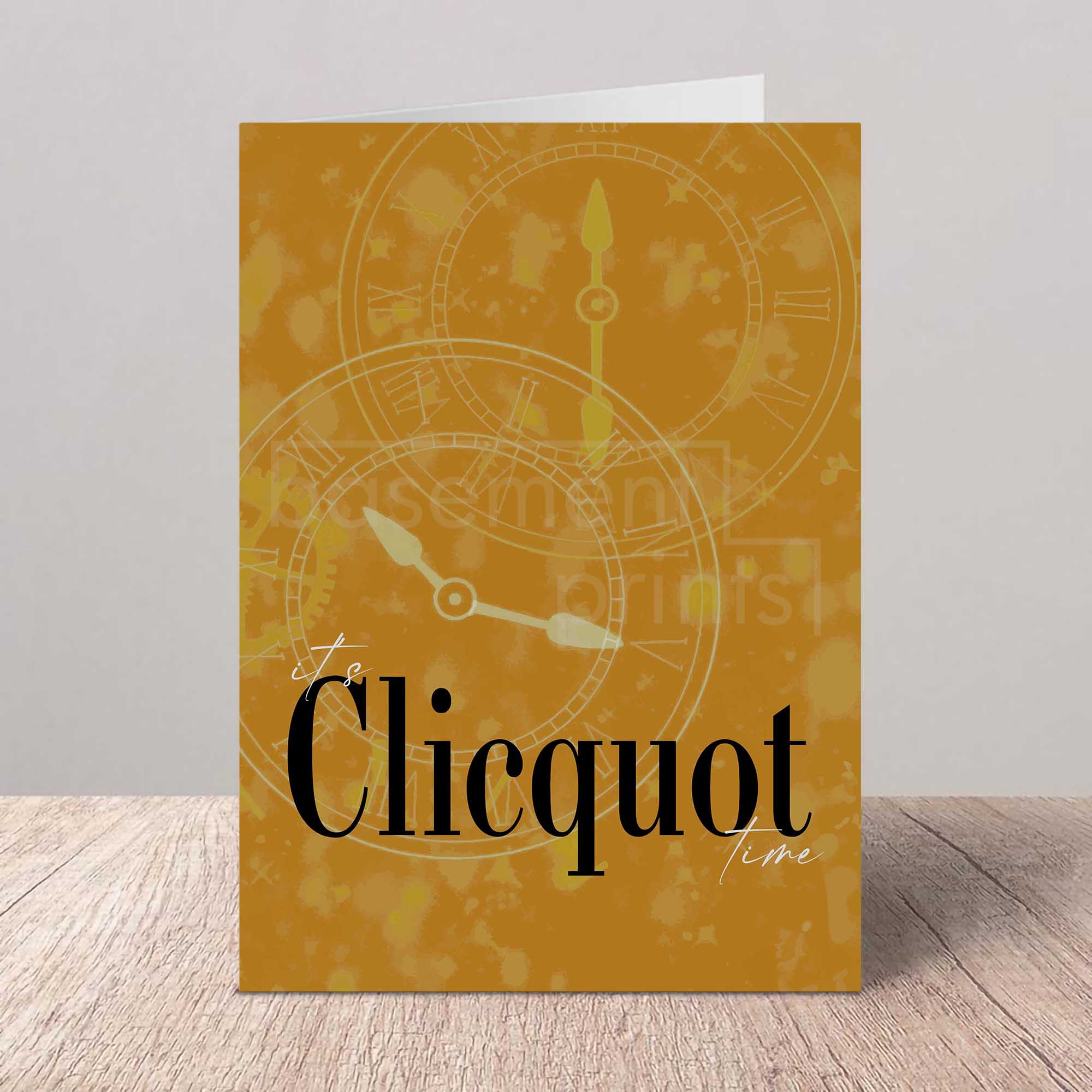Greeting card with 'It's Clicquot time' text and clock design on a wooden surface.
