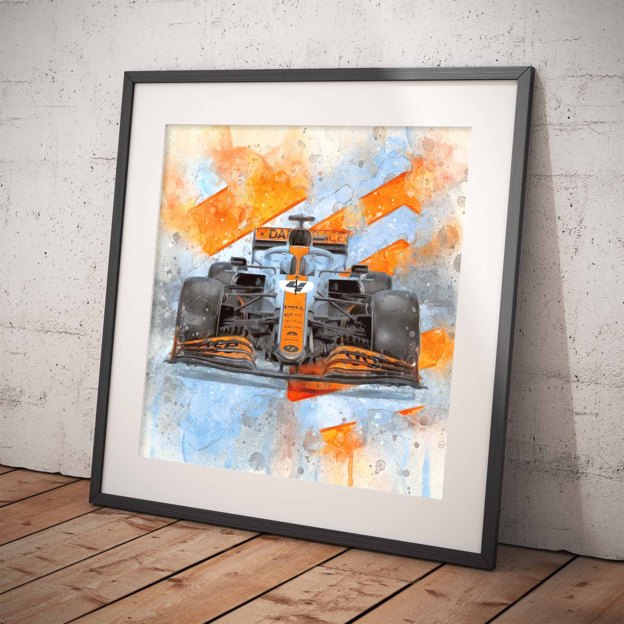 Framed artwork of a McLaren F1 car in Gulf Livery with orange and blue design on a white wall.