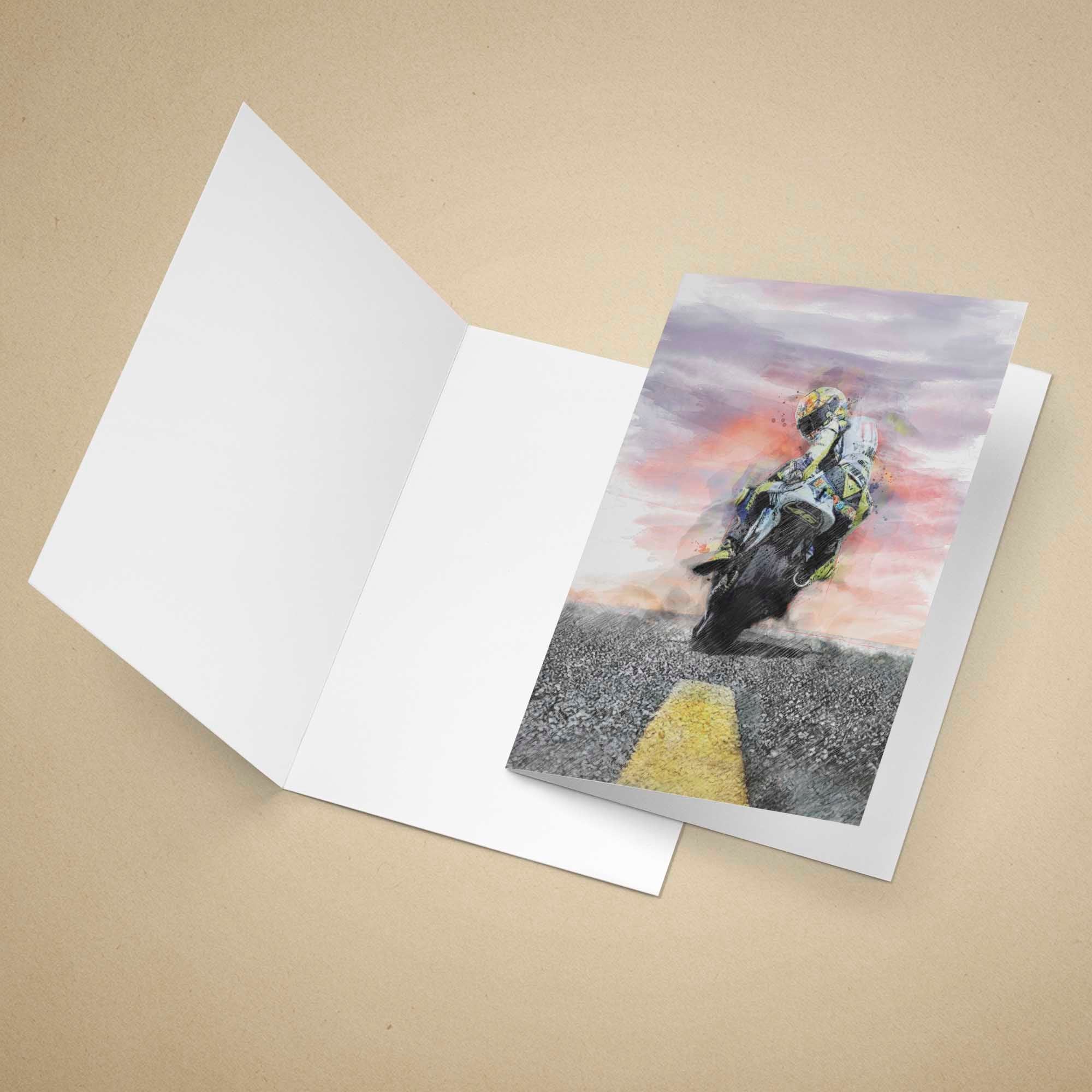 Greeting card with a motorcycle rider on a road design, placed inside an open white envelope on a beige background.