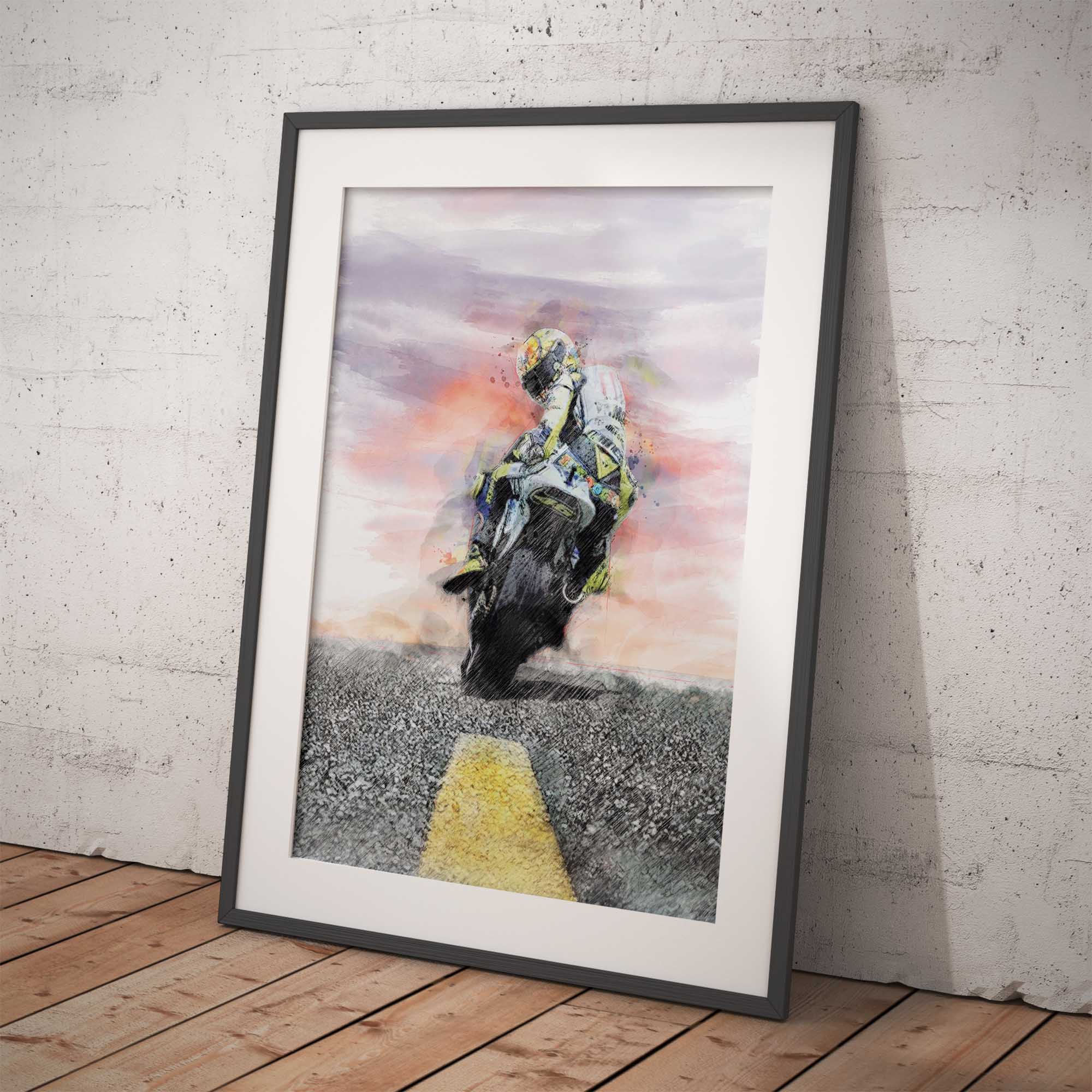Framed artwork of a motorbike rider against a colourful sky, leaning against a white brick wall.