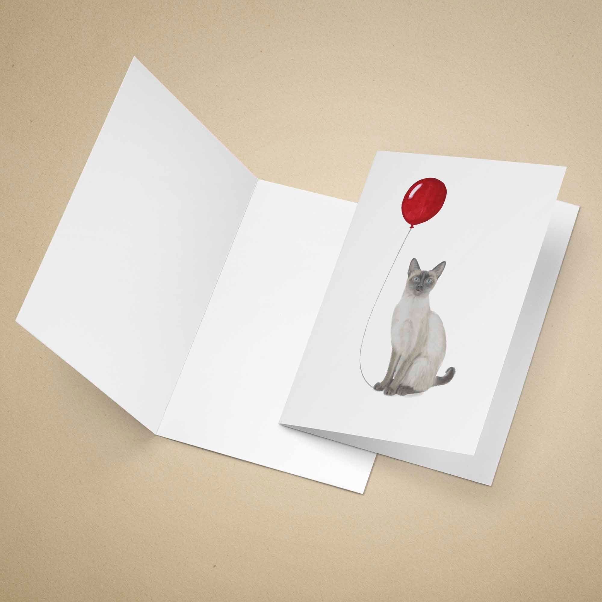 Greeting card with a cat holding a red balloon on a beige background