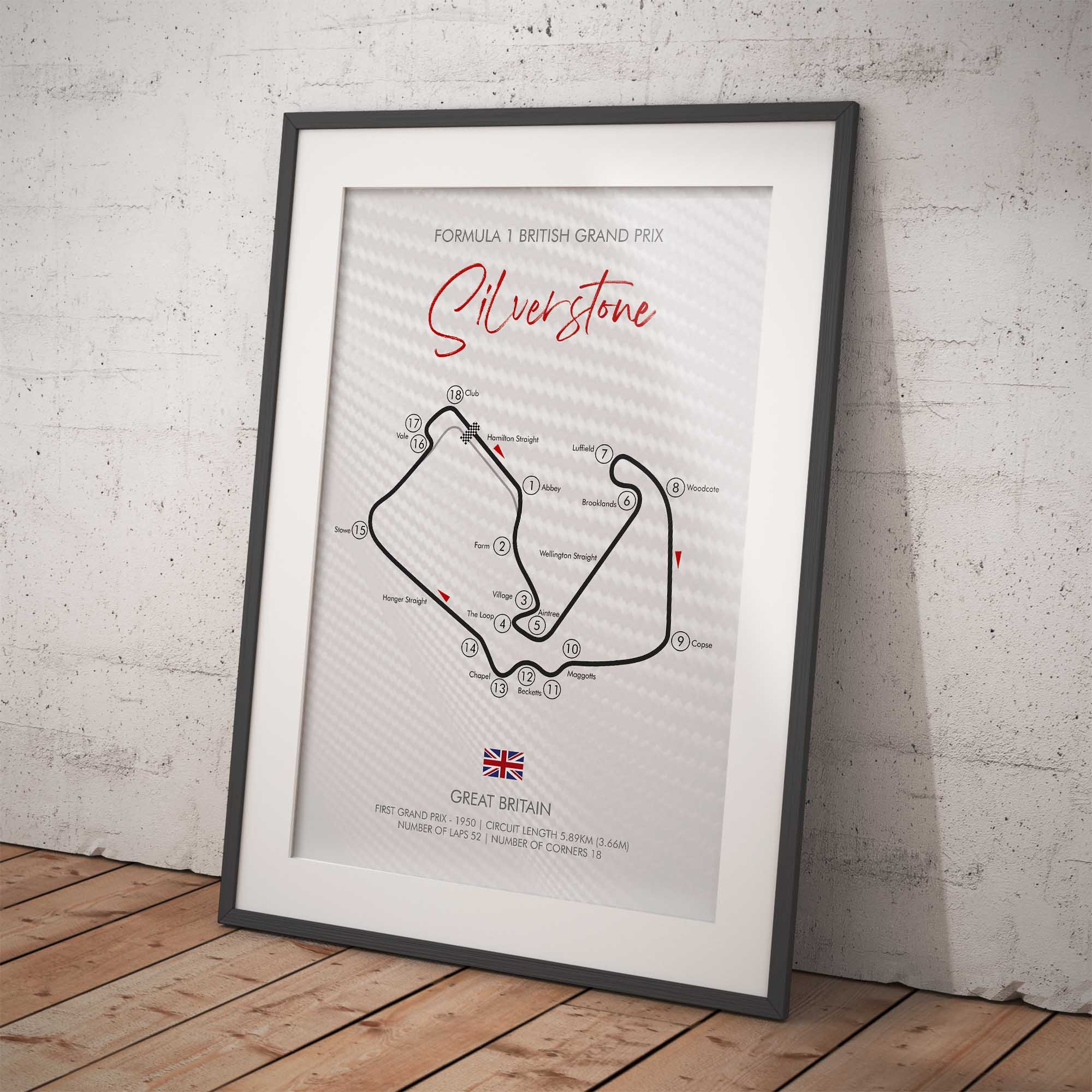 Framed poster of Silverstone circuit layout on a white brick wall.