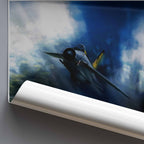 A rolled poster or wall art print showing a vintage fighter jet flying through dramatic blue and white clouds, photographed against a dark gray background.