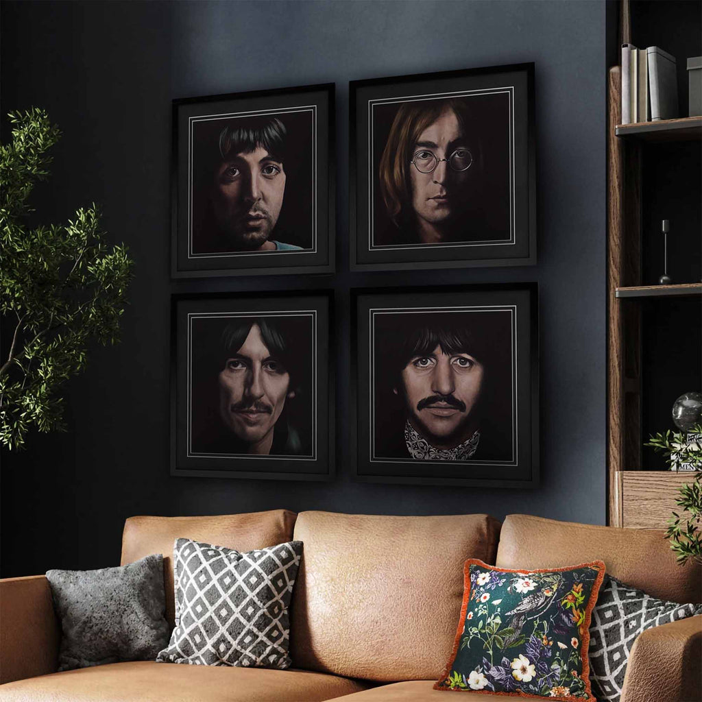 Framed portraits of each member of The Beatles on a wall above a couch with decorative pillows.