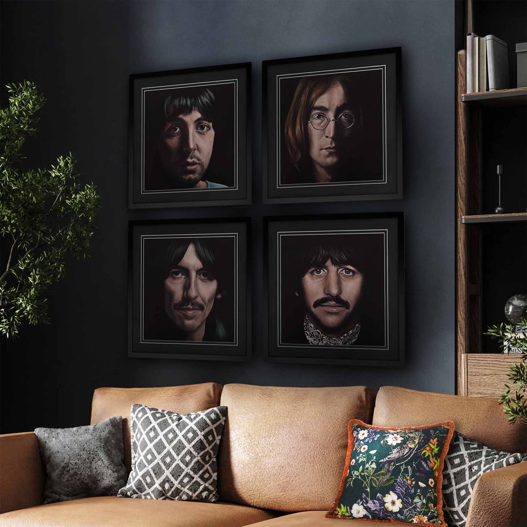 Framed portraits of each member of The Beatles on a wall above a couch with decorative pillows.
