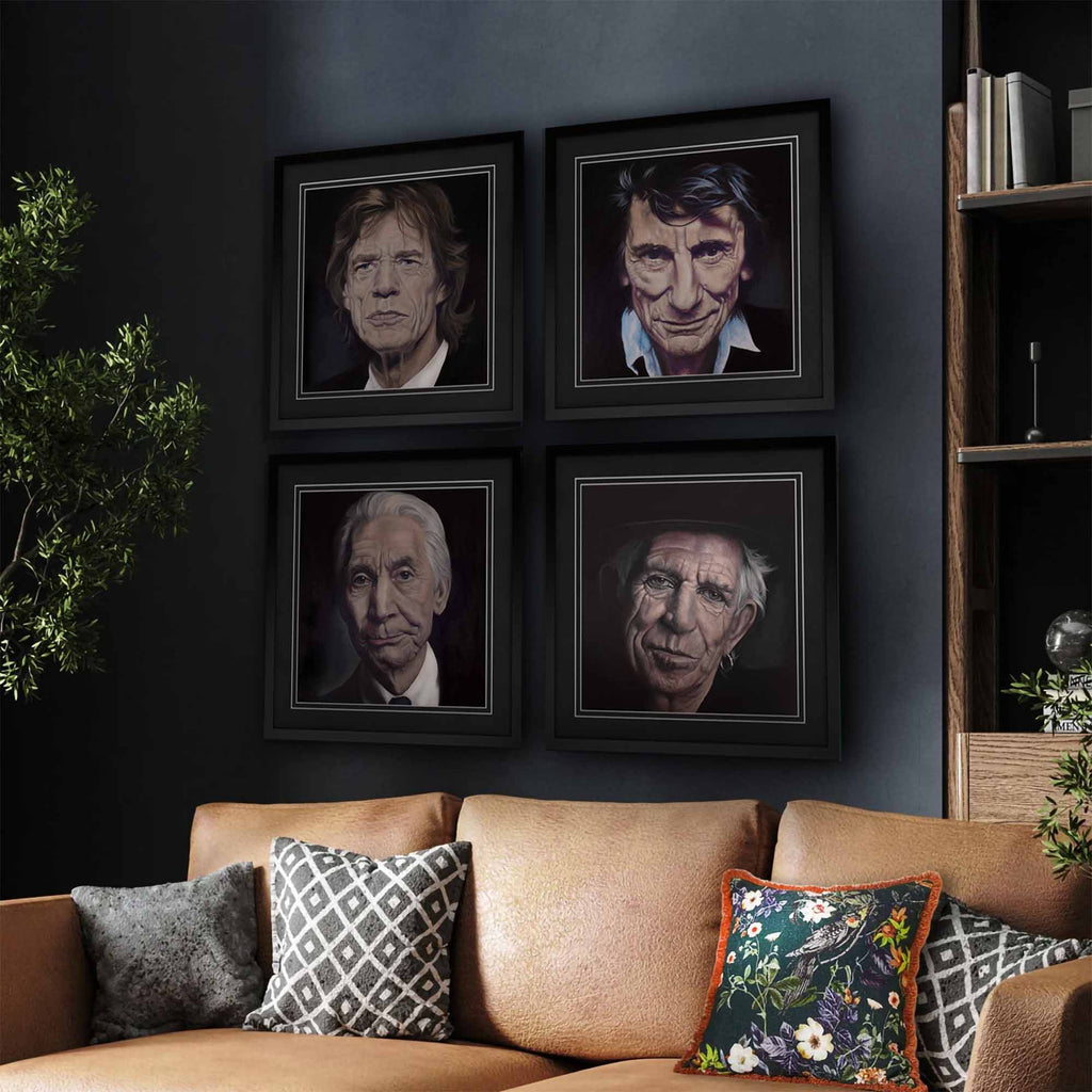 Framed portraits of each member of The Rolling Stones on a wall above a couch with decorative pillows.