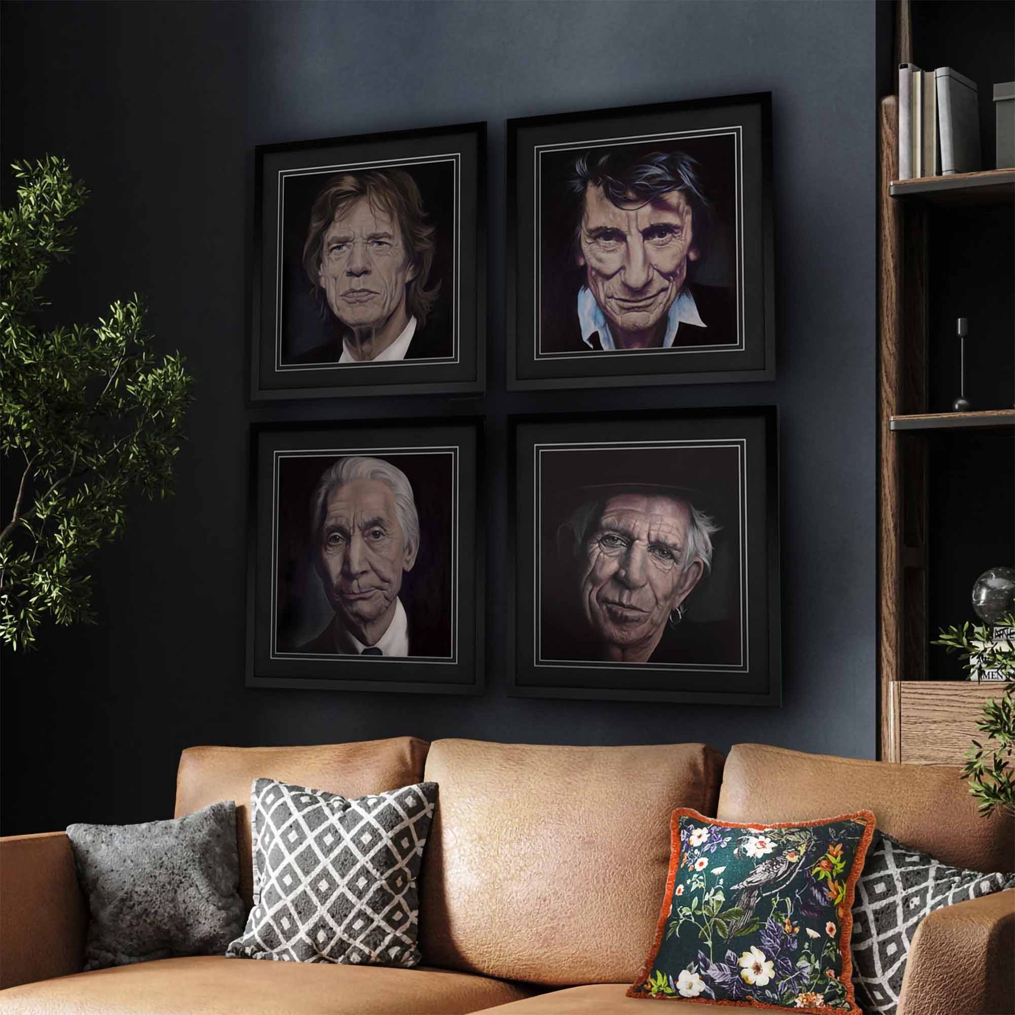 Framed portraits of each member of The Rolling Stones on a wall above a couch with decorative pillows.