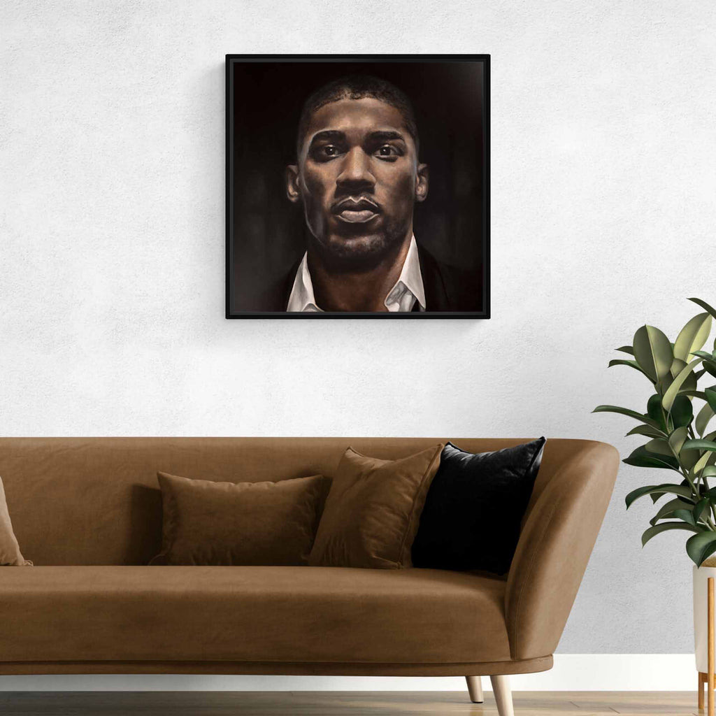Framed portrait of Anthony Joshua above a brown sofa with decorative pillows in a living room setting.