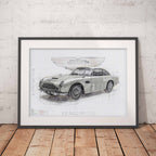Framed blueprint of an Aston Martin DBS on a wooden floor with a white brick wall background