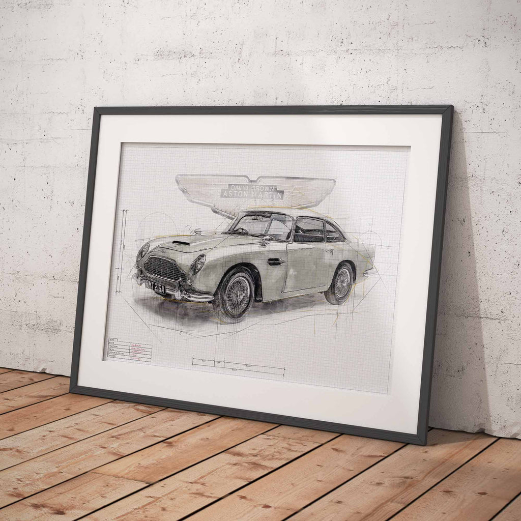 Framed artowrk of James Bonds Aston Martin DB5 car blueprint on a wooden floor against a white brick wall.