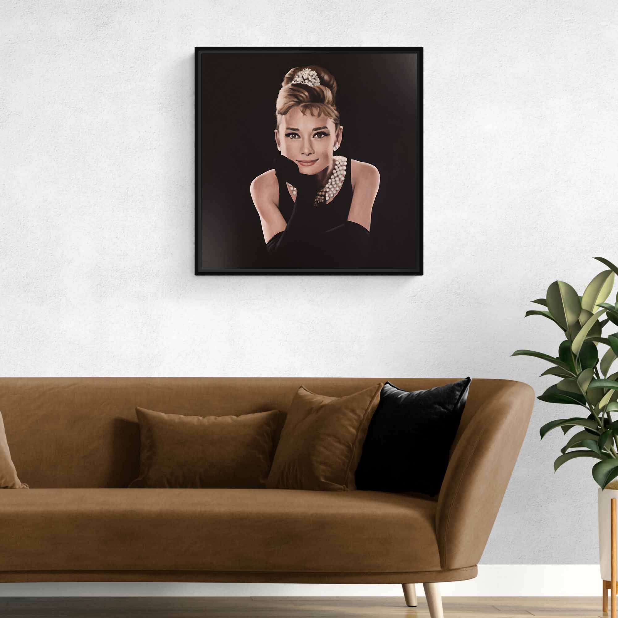 Framed portrait of Audrey Hepburn on a wall above a brown sofa with decorative pillows.