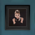Framed artwork of a stylized portrait of Audrey Hepburn with a blue background
