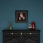 Framed portrait of Audrey Hepburn above a black cabinet with decorative items against a blue wall
