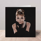 Greeting card of Audrey Hepburn in a black dress with a tiara on a white background.