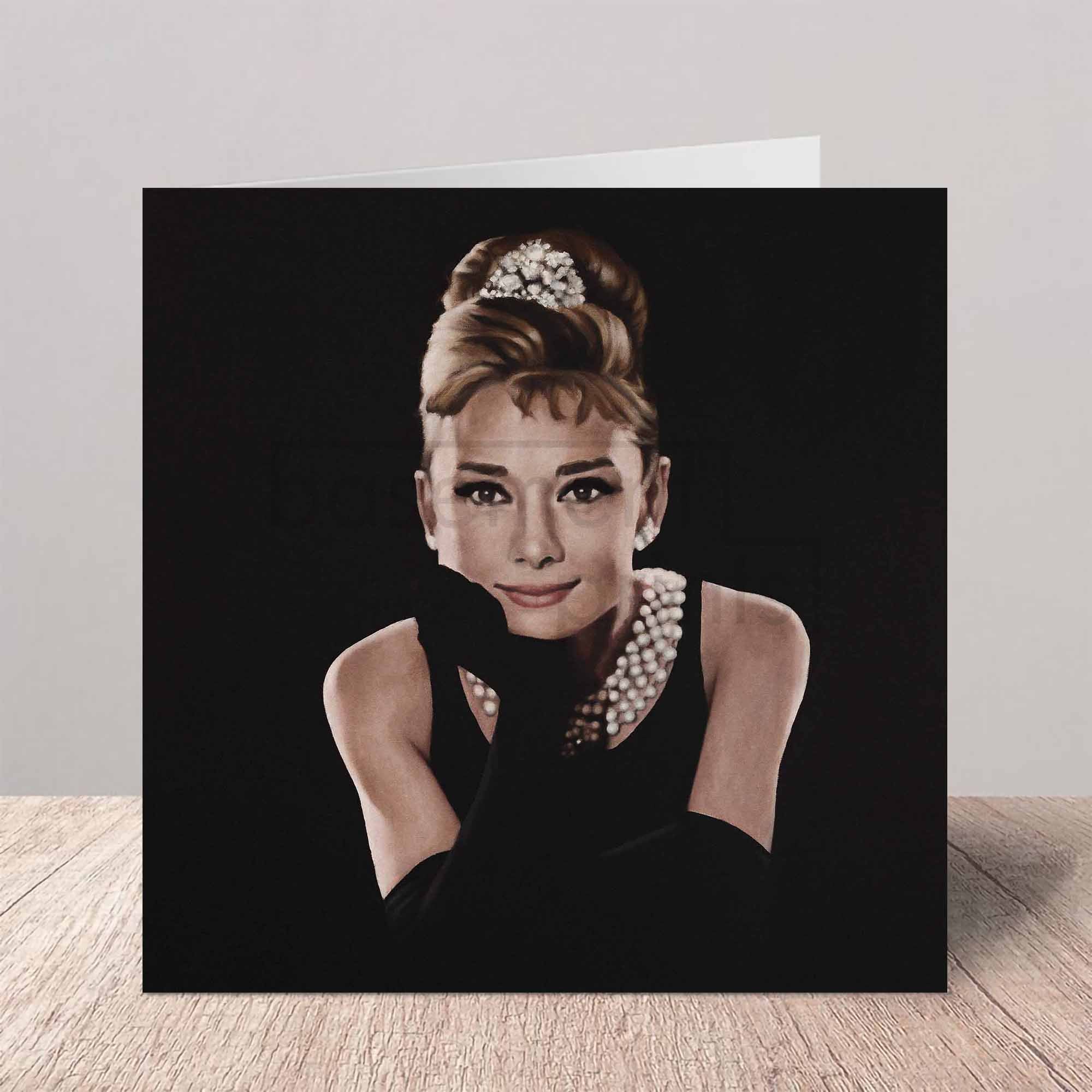 Greeting card of Audrey Hepburn in a black dress with a tiara on a white background.