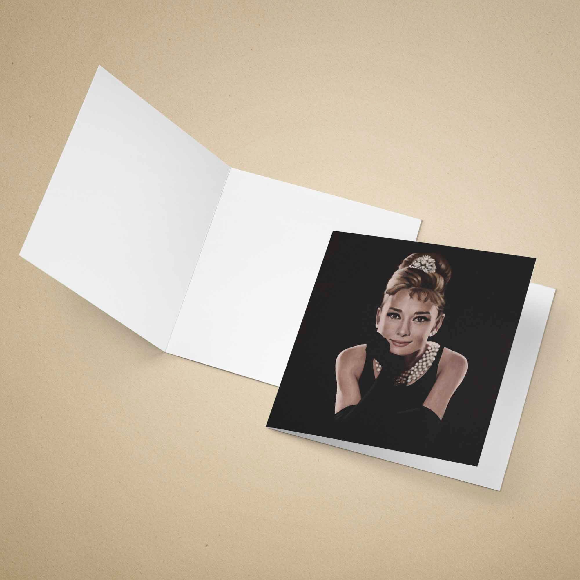 Greeting card of Audrey Hepburn in a black dress with a tiara on a beige background.