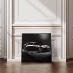 Framed artwork of James Bonds Aston Martin DB10 against a wall in a room with wooden flooring and white walls.