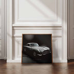 Framed artwork of James Bonds Aston Martin DB5 against a wall in a room with wooden flooring and white walls.