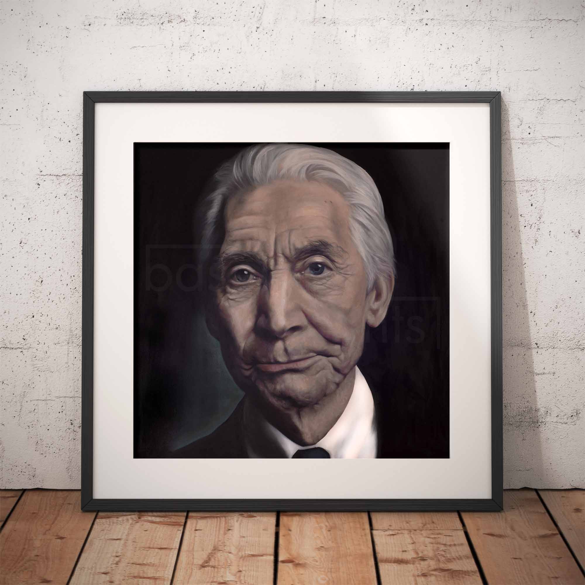 Framed portrait of Charlie Watts on a wooden floor with a white brick wall background