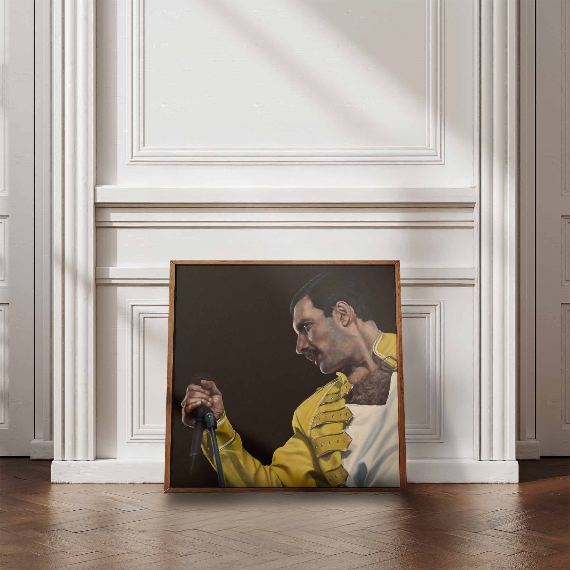 Framed portrait of Freddie Mercury in a yellow jacket against a white wall.