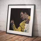 Framed portrait of Freddie Mercury in a yellow jacket against a dark background, leaning against a textured white wall.