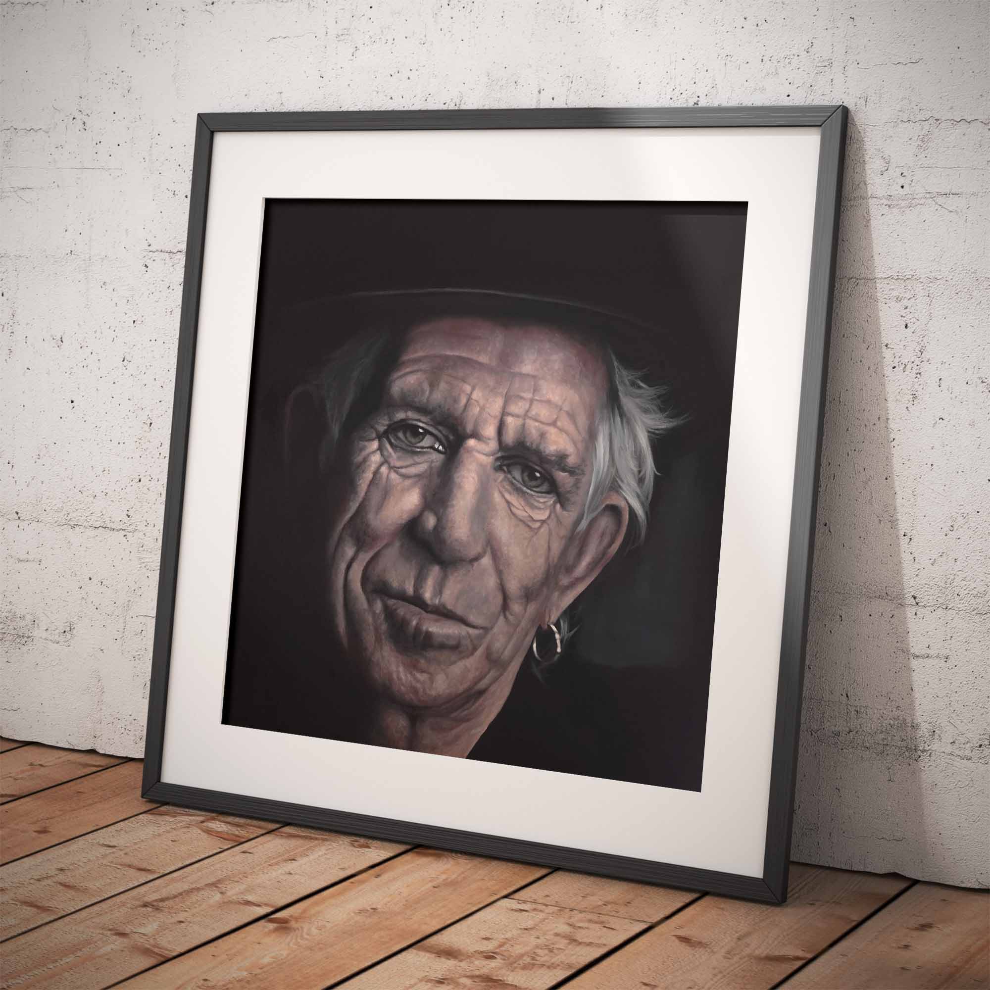 Framed portrait of Keith Richards on a wooden floor with a white brick wall background