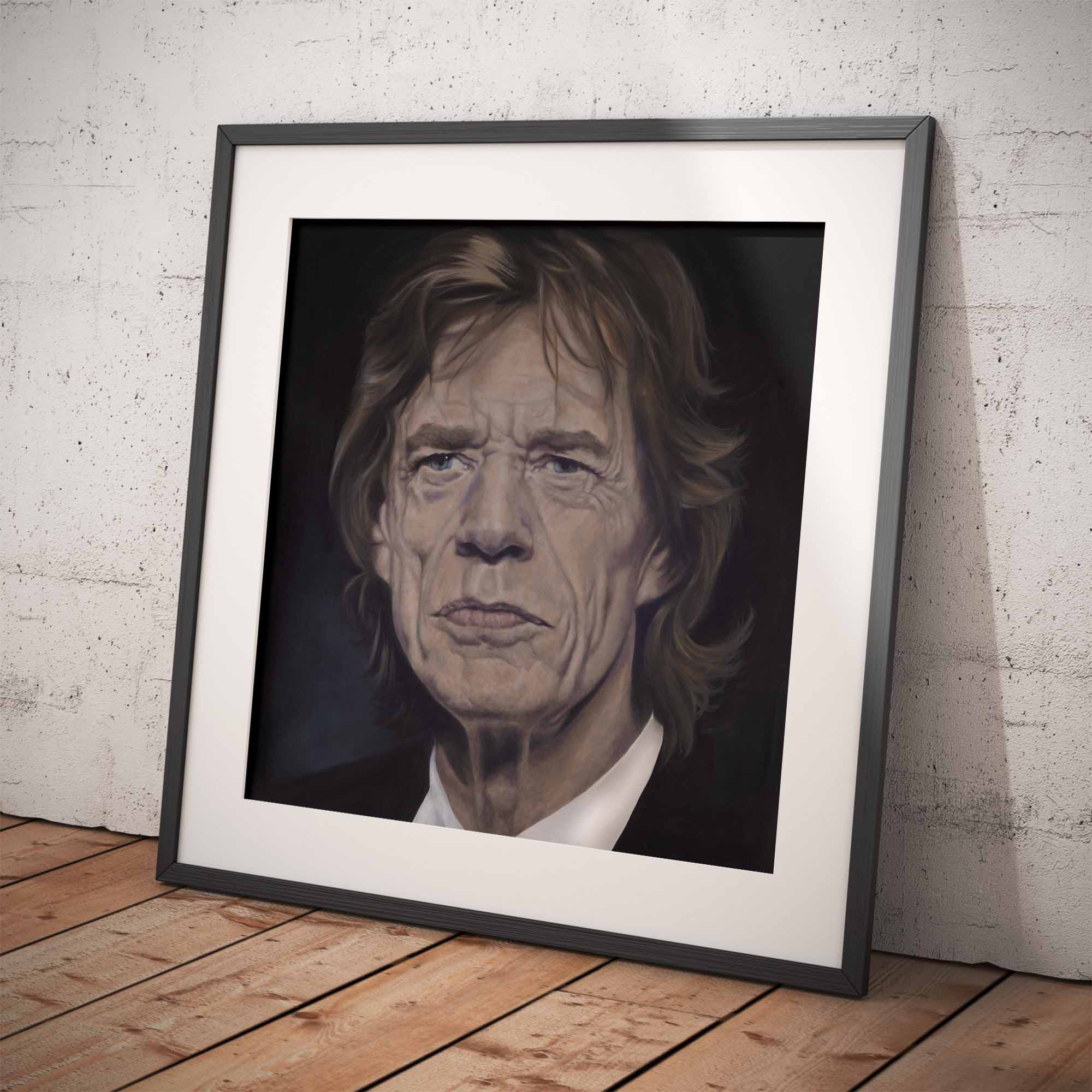 Framed portrait of Mick Jagger on a wooden floor with a white brick wall background