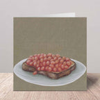 A square greeting card featuring a realistic oil painting of baked beans on toast, standing on a wooden surface against a neutral background.