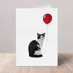 Greeting card with a black and white cat holding a red balloon on a white background
