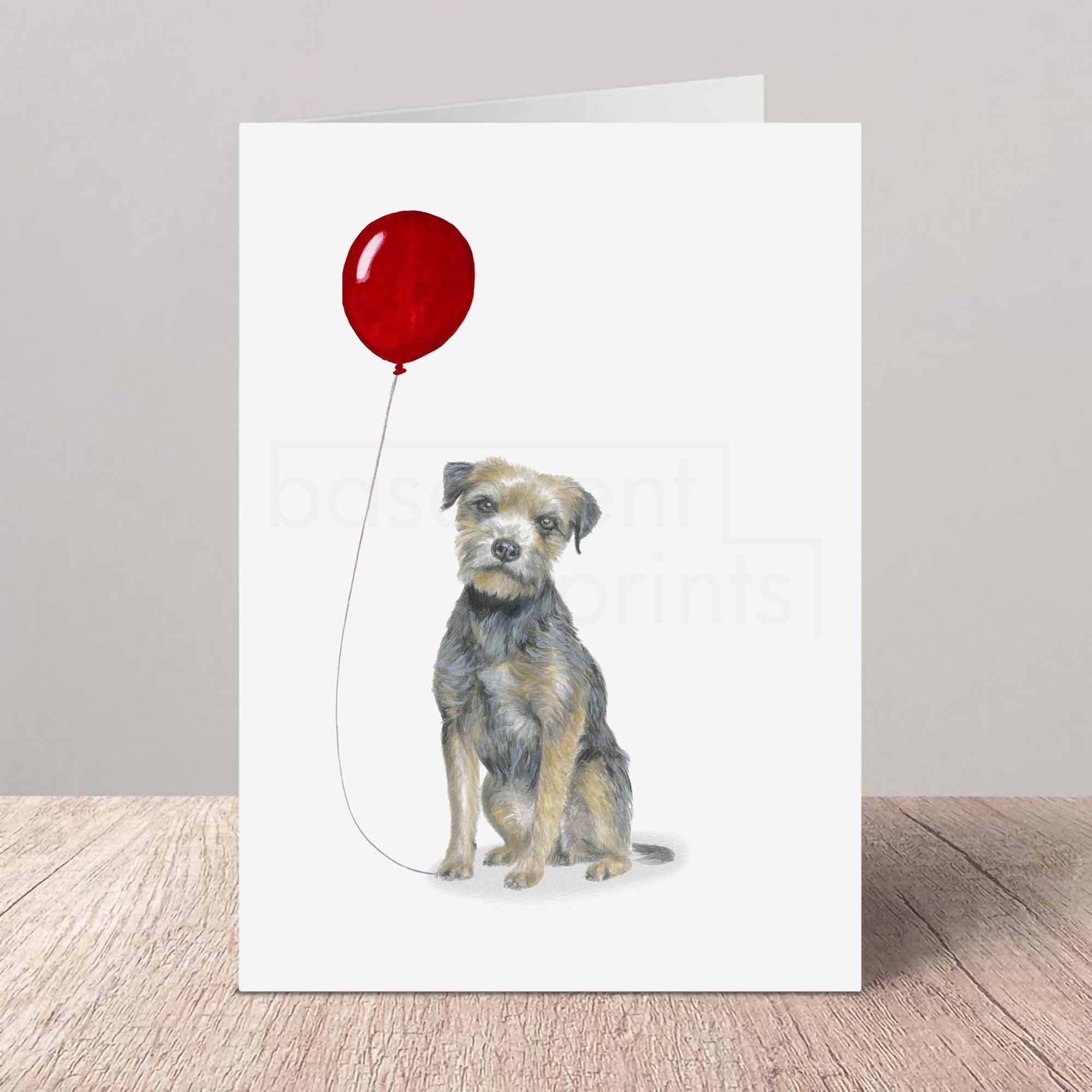 Greeting card with a Border Terrier holding a red balloon on a white background