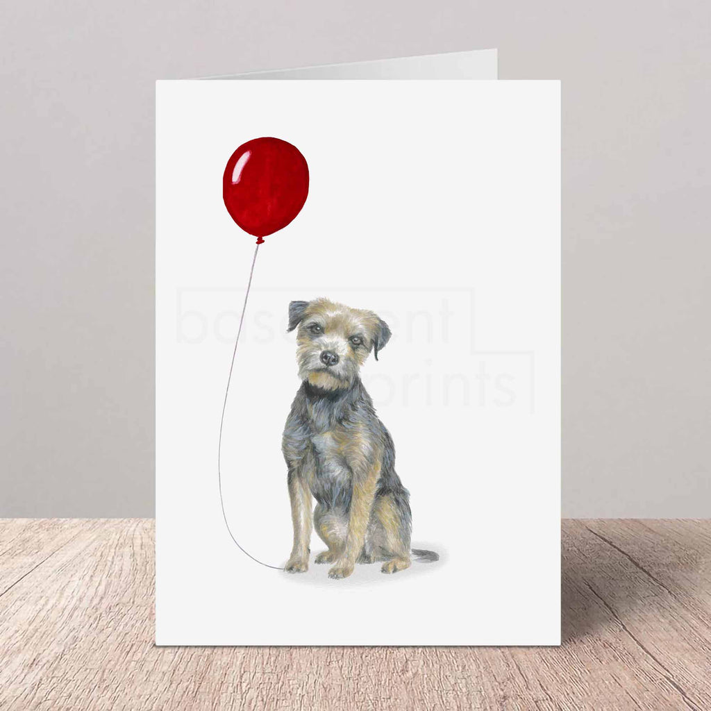 Greeting card with a Border Terrier holding a red balloon on a white background