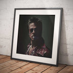 Framed artwork of Brad Pitt with sunglasses and a dark background on a wooden floor.