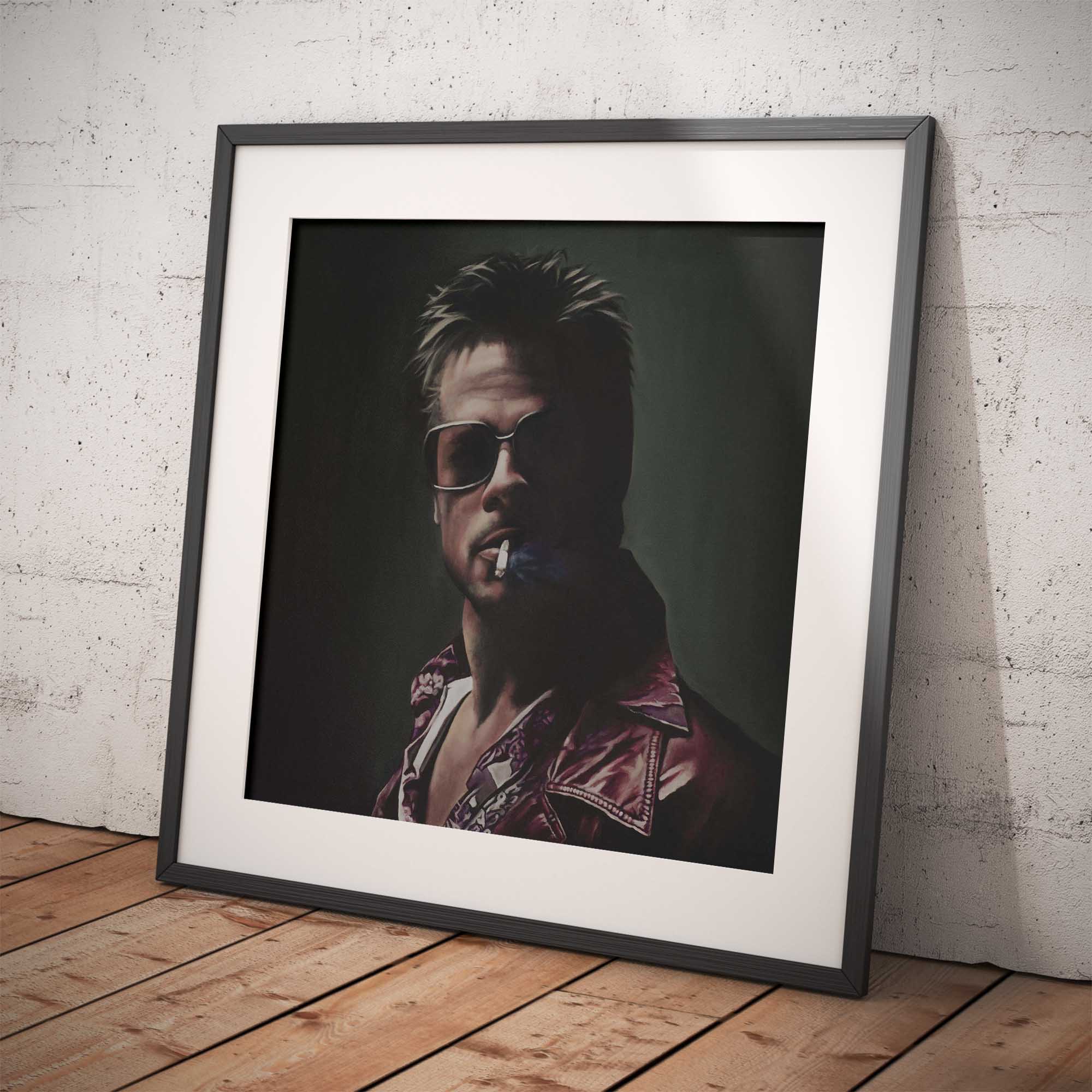 Framed artwork of Brad Pitt with sunglasses and a dark background on a wooden floor.