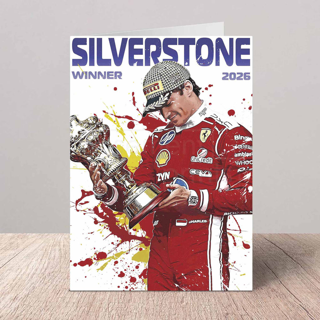 A vertical greating card against a light gray wall on a wood surface, featuring a stylised illustration of Charles Leclerc in a red Ferrari racing suit holding a trophy, with the text 'SILVERSTONE WINNER 2026' at the top.