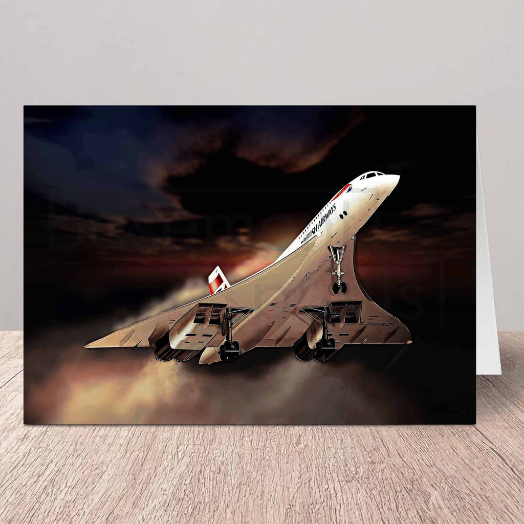 A greeting card featuring a dramatic illustration of a Concorde supersonic jet taking off against a dark, smoky sky, displayed on a light wood surface.