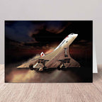 A greeting card featuring a dramatic illustration of a Concorde supersonic jet taking off against a dark, smoky sky, displayed on a light wood surface.