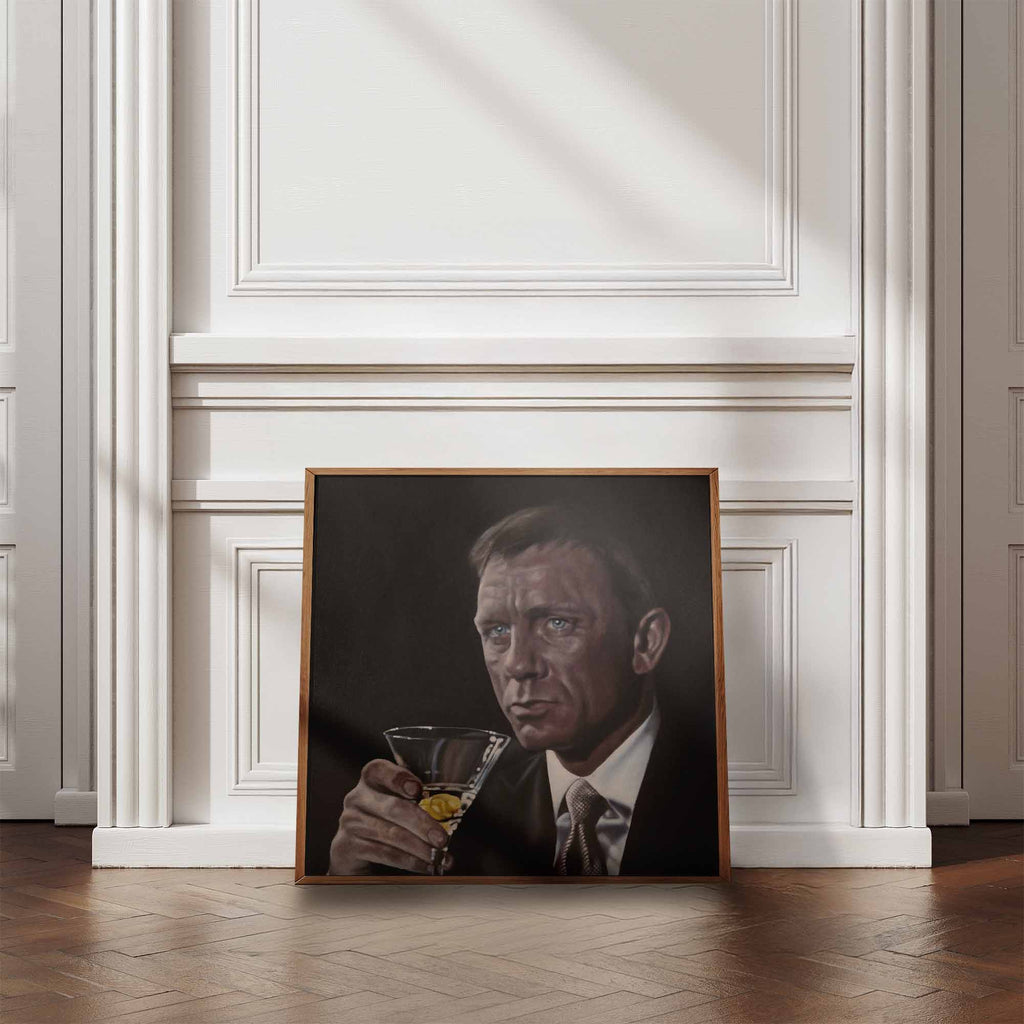Framed portrait of James Bond, Daniel Craig holding a cocktail in a room with white walls and wooden floor.