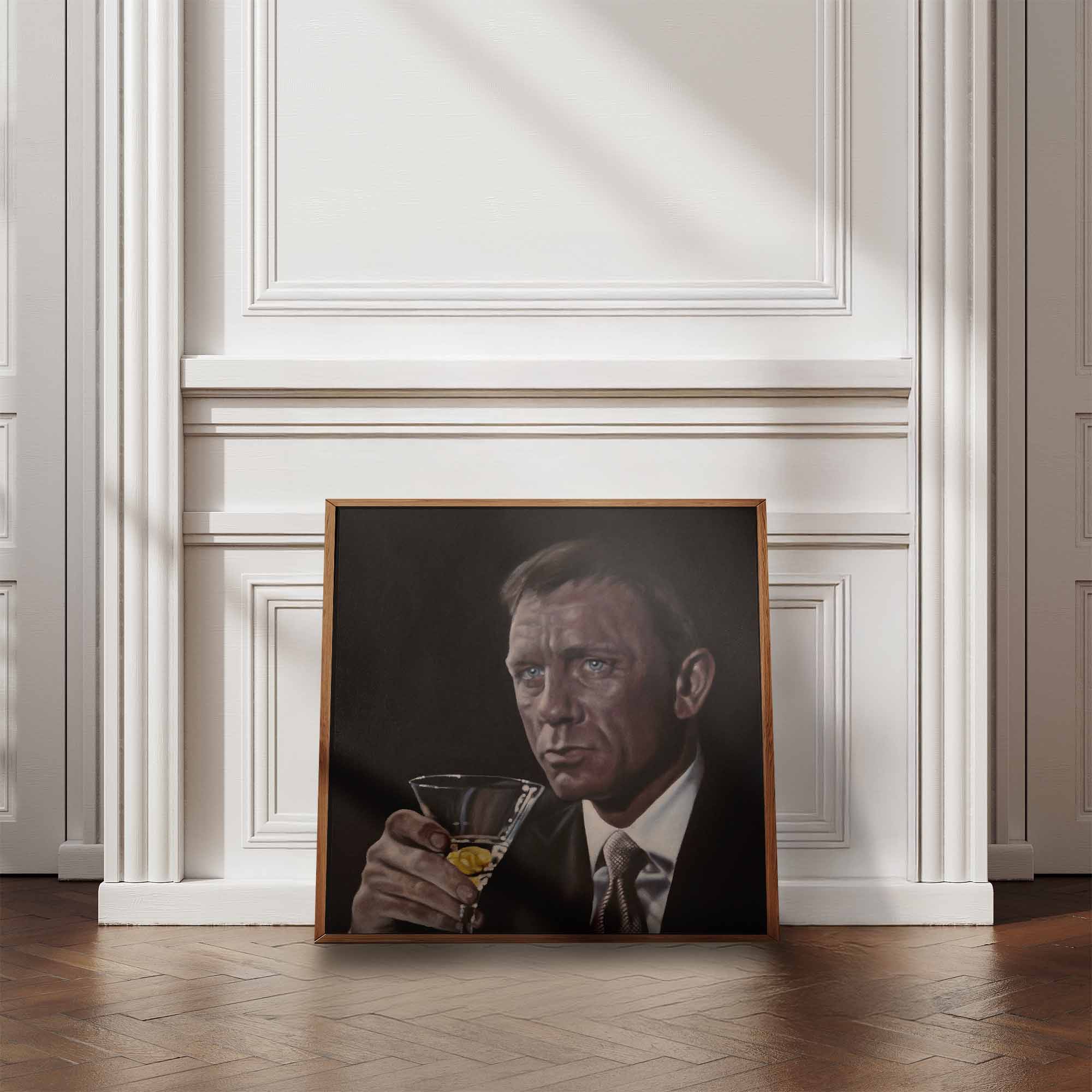 Framed portrait of James Bond, Daniel Craig holding a cocktail in a room with white walls and wooden floor.