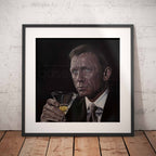 Framed artwork of James Bond, Daniel Craig holding a martini glass against a white brick wall.