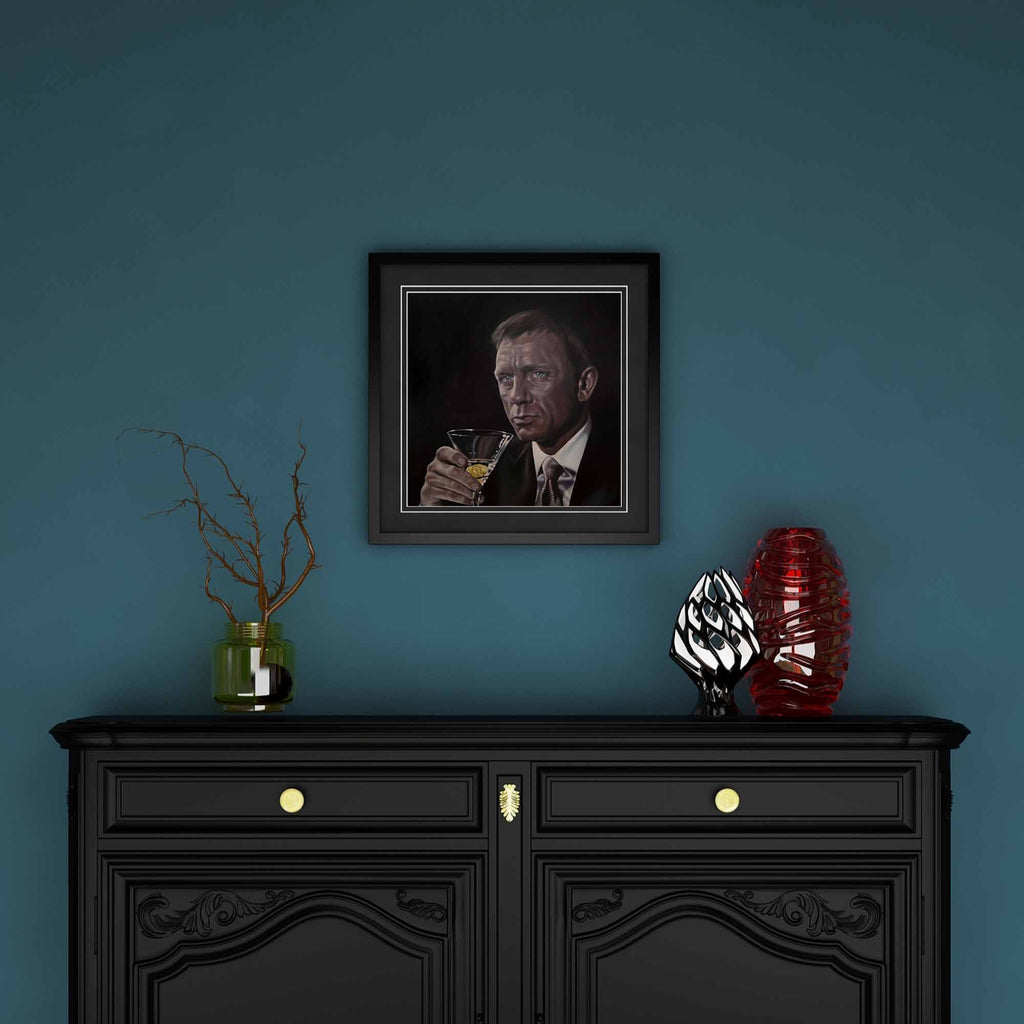 Framed portrait on a blue wall above a black cabinet with decorative items.