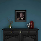 Framed portrait on a blue wall above a black cabinet with decorative items.
