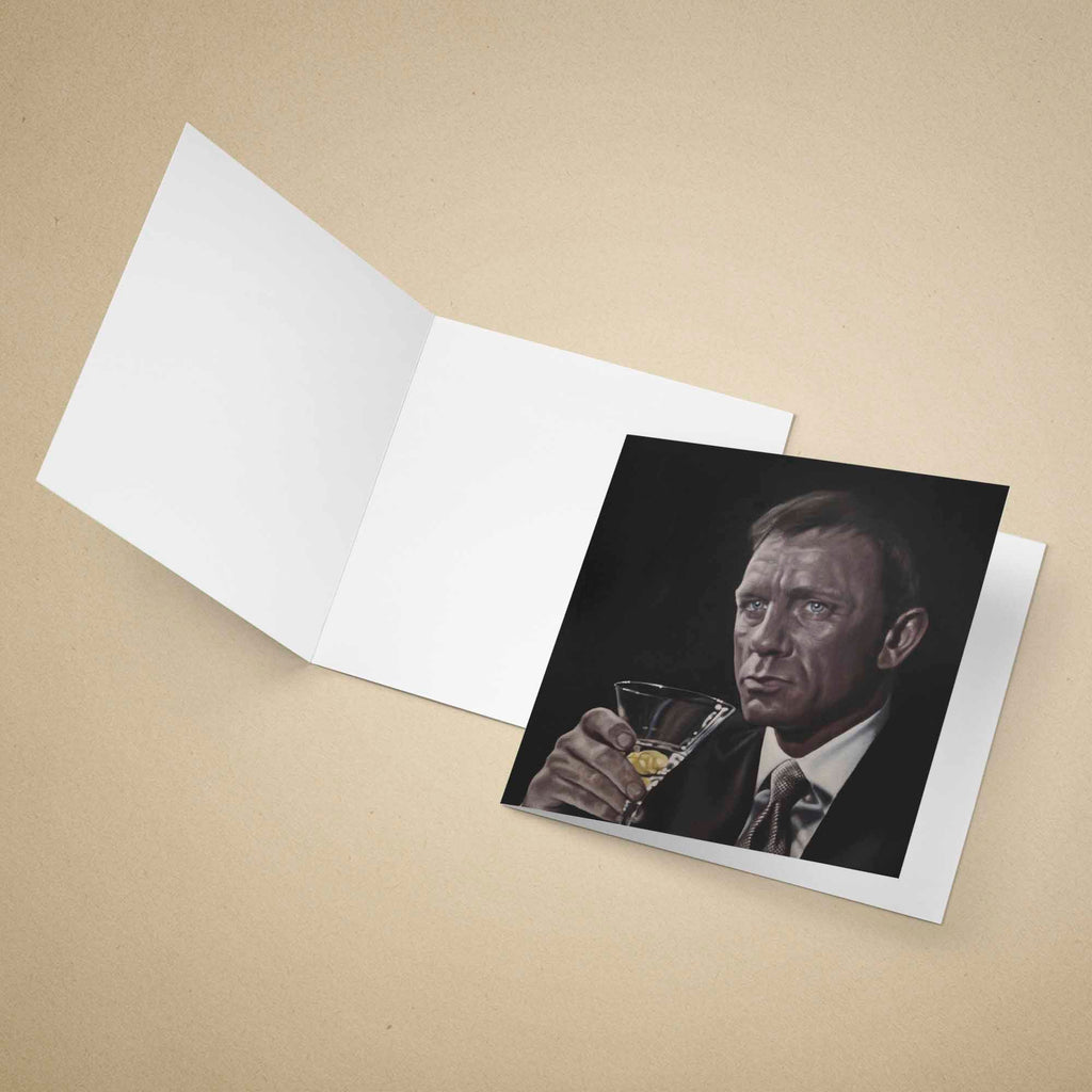 Greeting card Daniel Craig as James Bond holding a cocktail glass on a beige background
