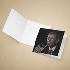Greeting card Daniel Craig as James Bond holding a cocktail glass on a beige background